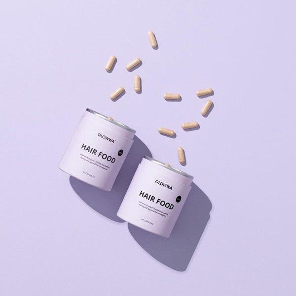 Two containers labeled 'Hair Food' with scattered capsules on a light purple background